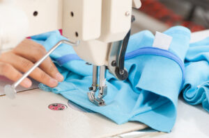 closeup seamstress on the machine sews clothes at a garment factory